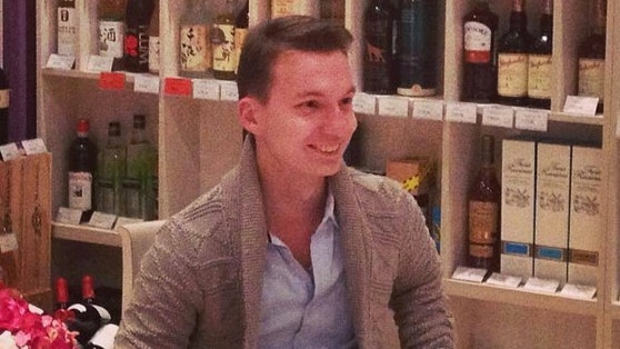 Aleksandr Ermakov sitting in a chair in what appears to be a high-end bottle shop