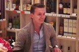 Aleksandr Ermakov sitting in a chair in what appears to be a high-end bottle shop