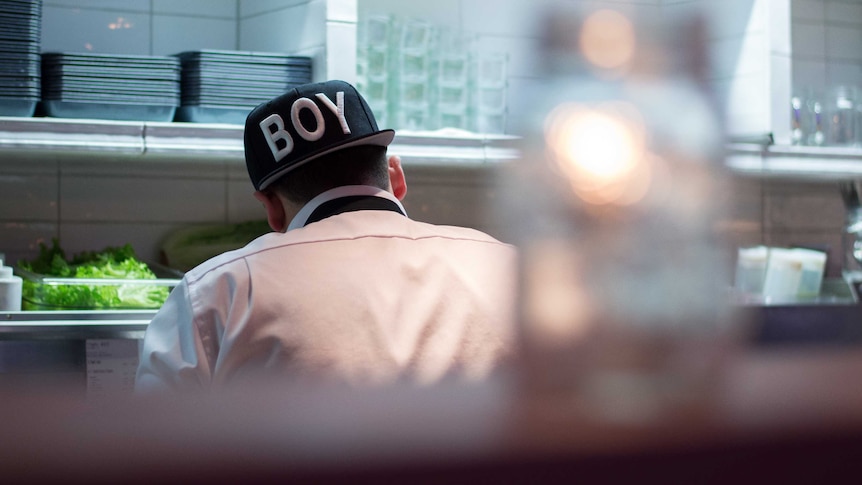 A man works in a commercial kitchen while wearing a cap, for a story on finding work when you have a criminal record.
