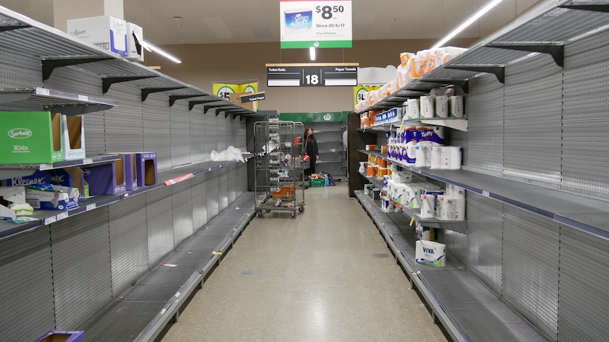 A bare aisle at Alice Springs Woolworths with only some packages of toilet paper left.