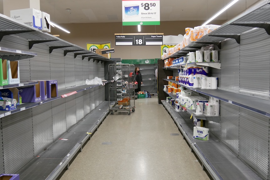 A bare aisle at Alice Springs Woolworths with only some packages of toilet paper left.