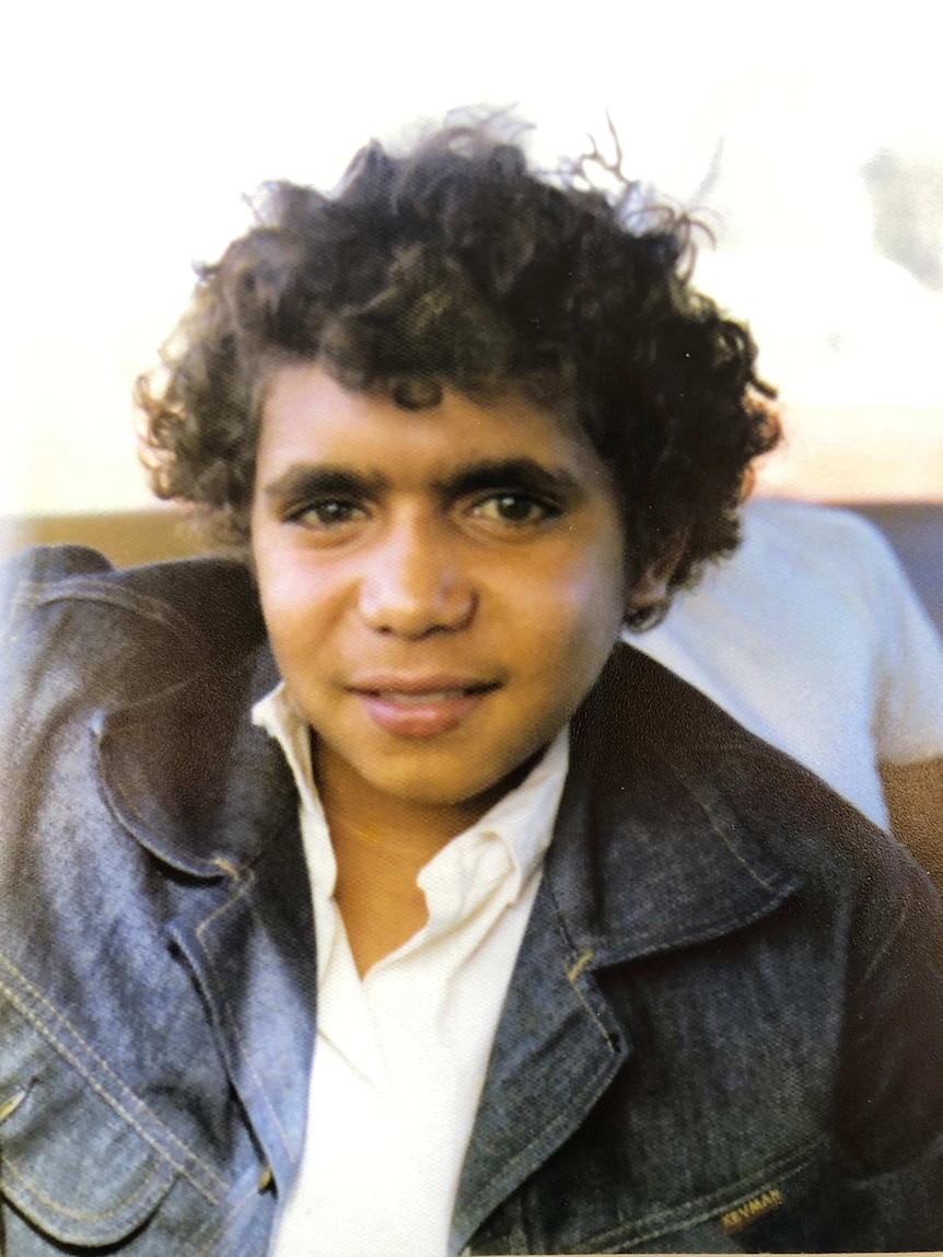 Old image of a teenage boy, wearing a white shirt and denim jacket.