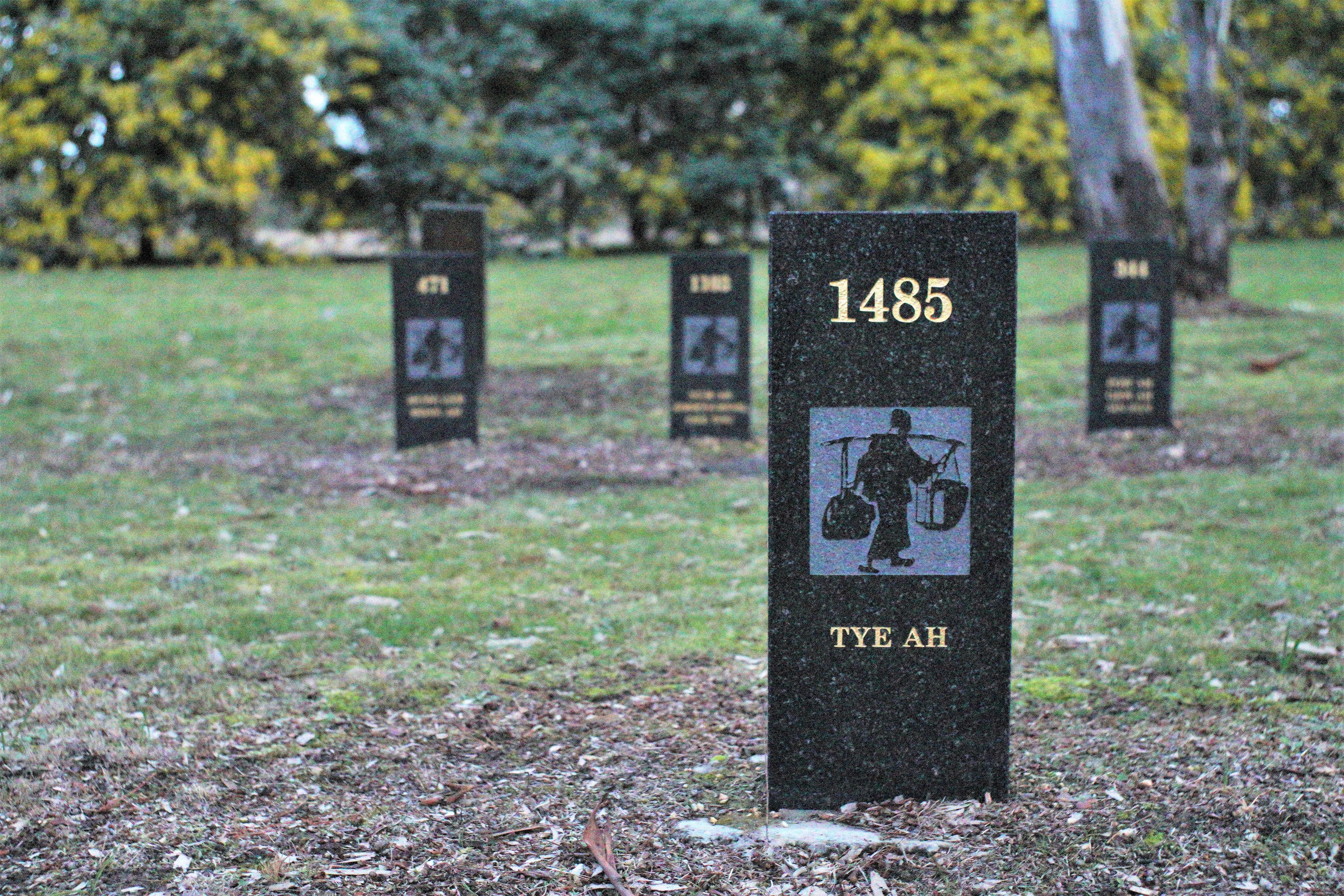 A bluestone headstone with a motif of a Chinese gold miner with the record number and name engraved
