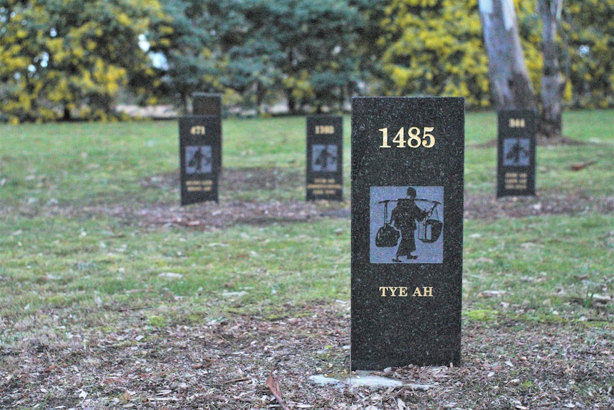 A bluestone headstone with a motif of a Chinese gold miner with the record number and name engraved