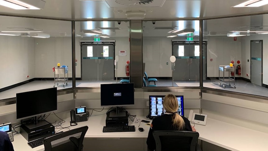 A nurse sits in a nursing station looking over an empty room.