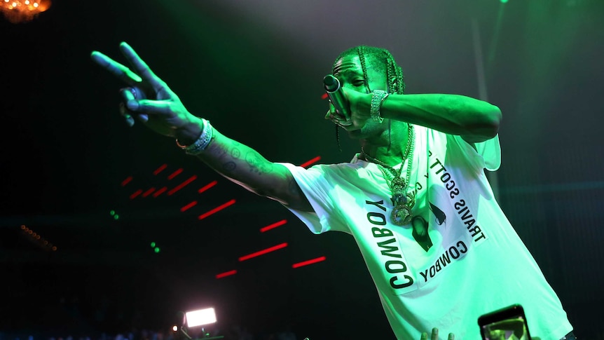 Travis Scott, a rapper, performs a peace sign for a crowd.