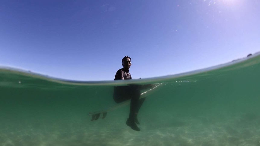 A South African man sits on his board in the green water.