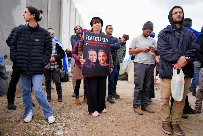 Woman holds a placard of Israeli hostages among a group[ 