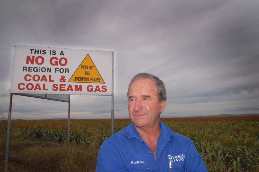 Farmer Andrew Pursehouse stands in front of a sign reading "This is a no go region for coal and coal seam gas"