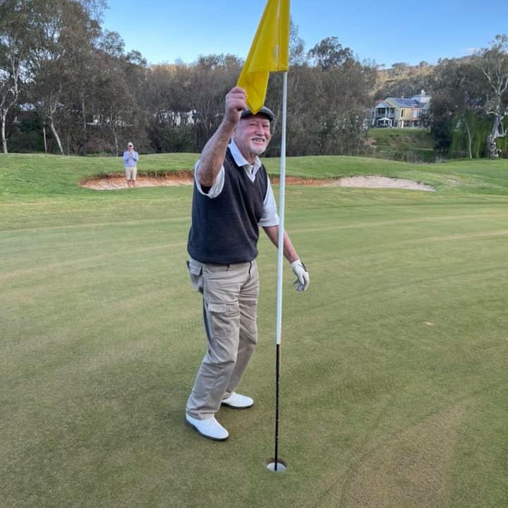 Man holding yellow flag on gold course smiling