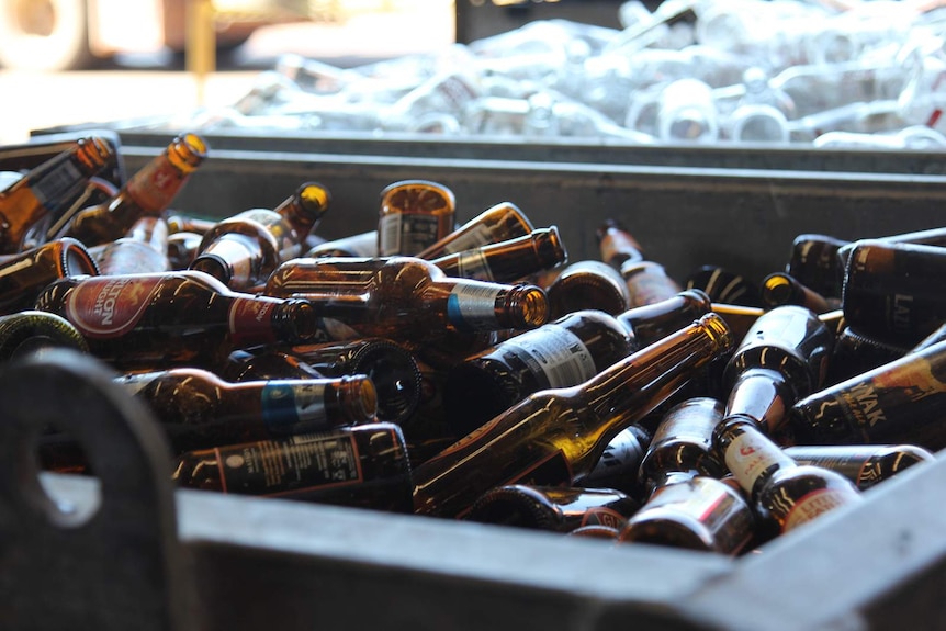 A photo of glass bottles in a big skip.