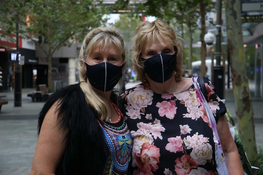 Two women wearing black face masks look at the camera in the Perth CBD.