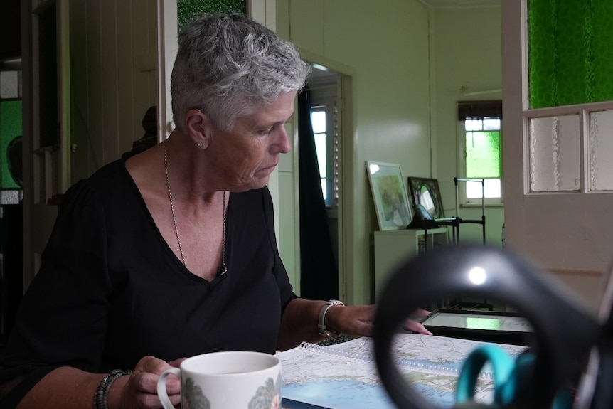 A woman with short grey hair looks over a map of Australia