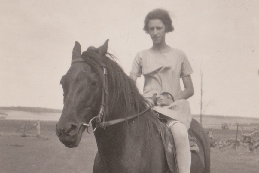 A black-and-white image of teenage girl on a horse.