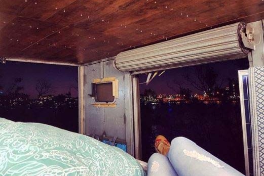 Chrissie Junge lays inside the back of her truck looking at the Brisbane skyline at night.