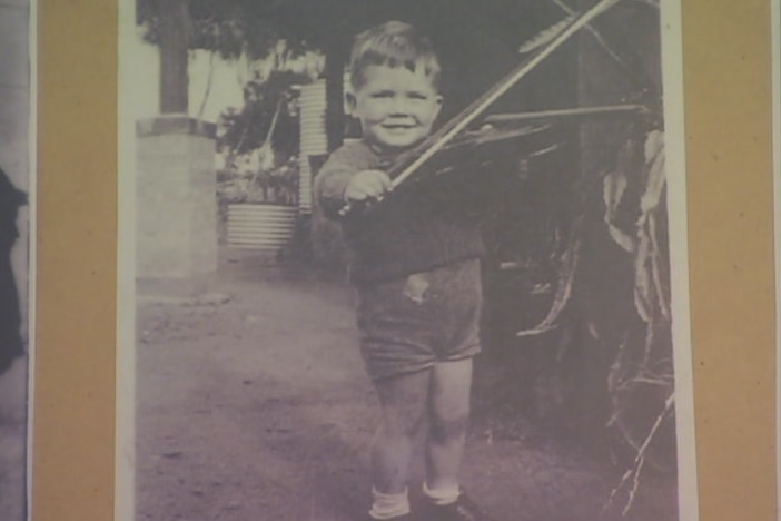 A black and white photo of a young child posing with a violin