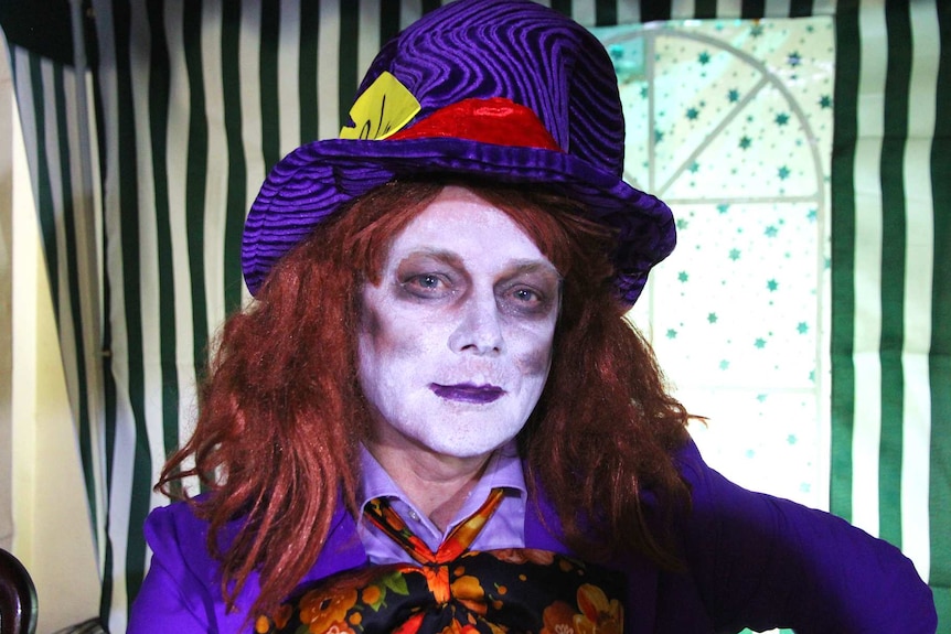 An actor is dressed as the Hatter - complete with bright wig and facepaint