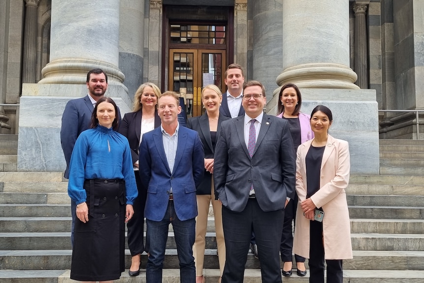 A group of people stand on the steps of South Australian parliament smiling at the camera