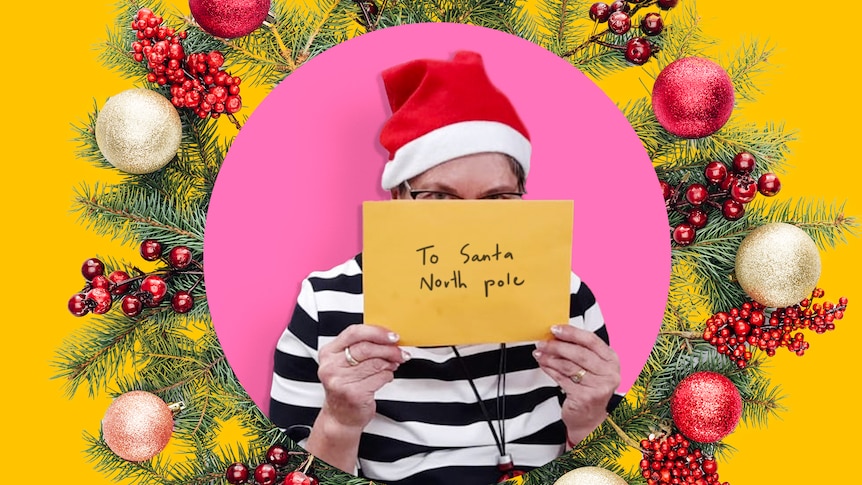A woman wearing a Santa hat holds a letter to Santa in the North Pole over her face