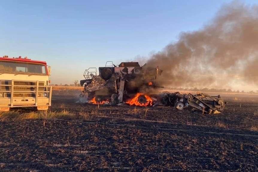 A wheat harvester burning in a paddock