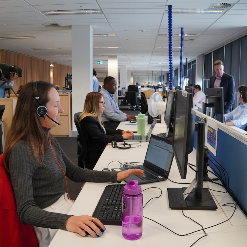 Recruitment staff sitting in a line at desks with headsets 