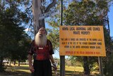 Uncle Willie Dixon looks off camera below the sign to the Bomaderry Aboriginal Children's Home.