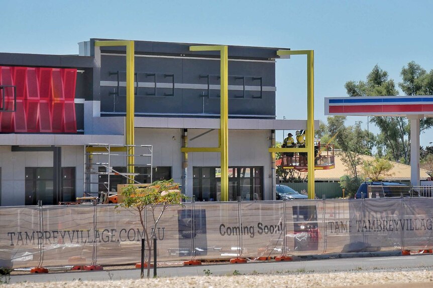A new building under construction in Karratha with workers on a scaffold inspecting part of the structure.