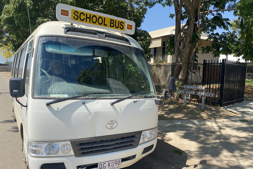 A white school mini-bus parked outside the Kowanyama Aged Care Services facility.