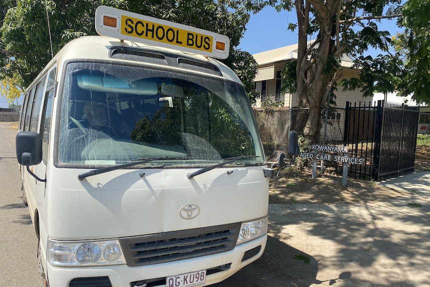 A white school mini-bus parked outside the Kowanyama Aged Care Services facility.