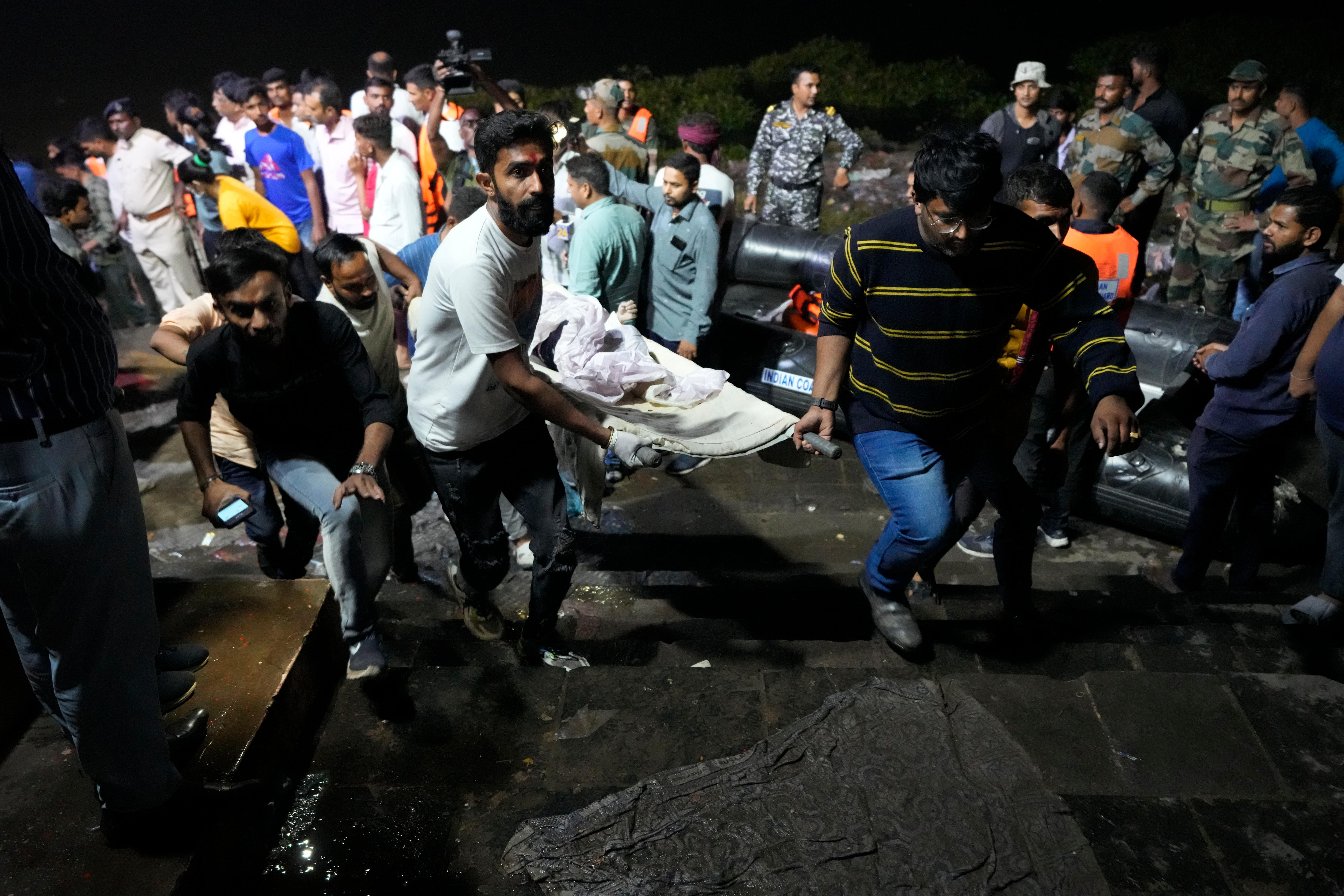 People carry a stretcher through a crowd at night time