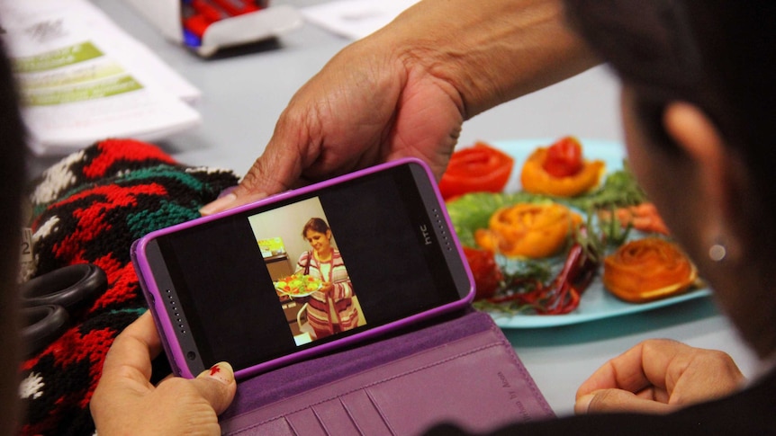 A woman shows a picture to another woman on her phone.