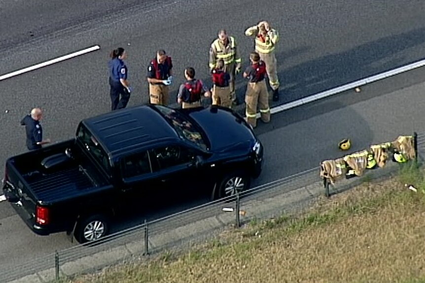 A group of firefighters standing near a black four-wheel drive ute on the Monash Freeway, pictures from above.