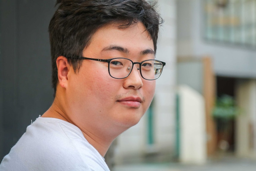 Close up of man in glasses looking over his shoulder to the camera