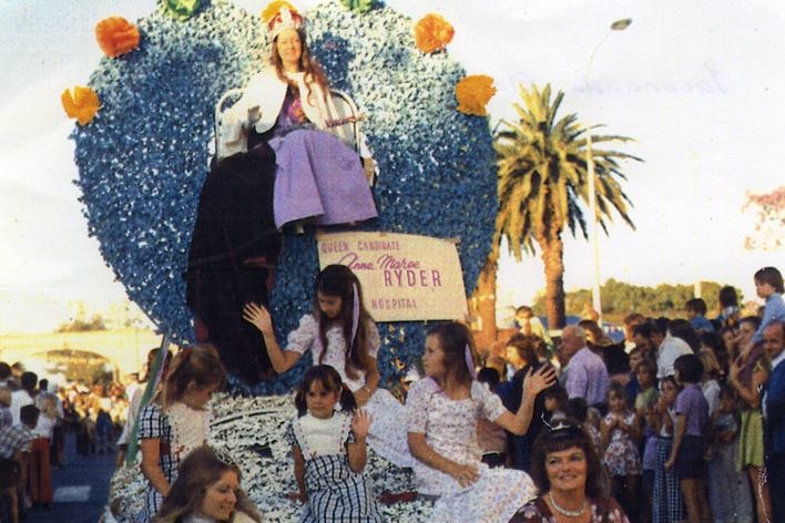 An old photo shows the Jacaranda Queen sitting on a home-made thrown while riding a float through the festival.