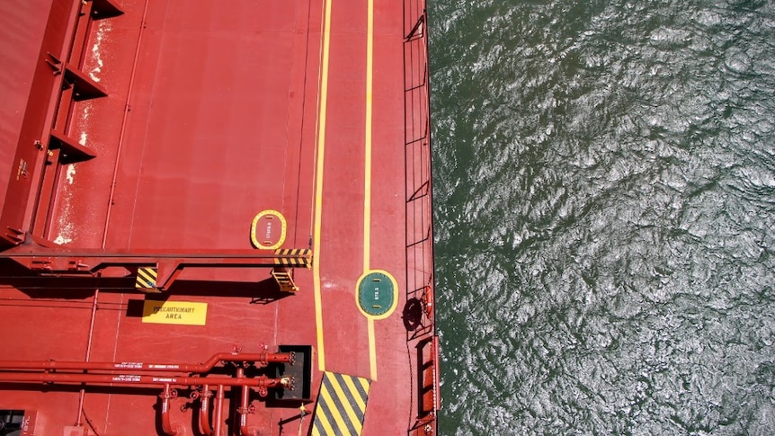 a top down view of a bright red panamax ship with a view of the ocean to the side