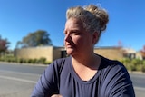 Woman standing in front of a road looking away from the camera 