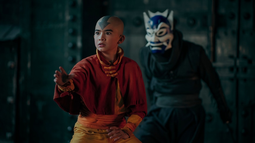 A TV still of Gordon Cormier, a Canadian Filipino teenager dressed as Avatar, poised for a fight. A man in a mask looms behind.