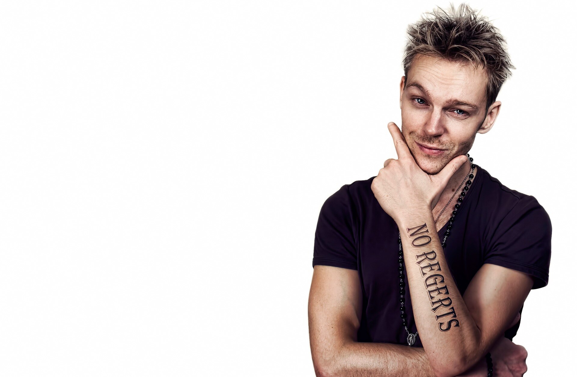 Man with a tattoo on his arm that says 'No regrets' spelled incorrectly