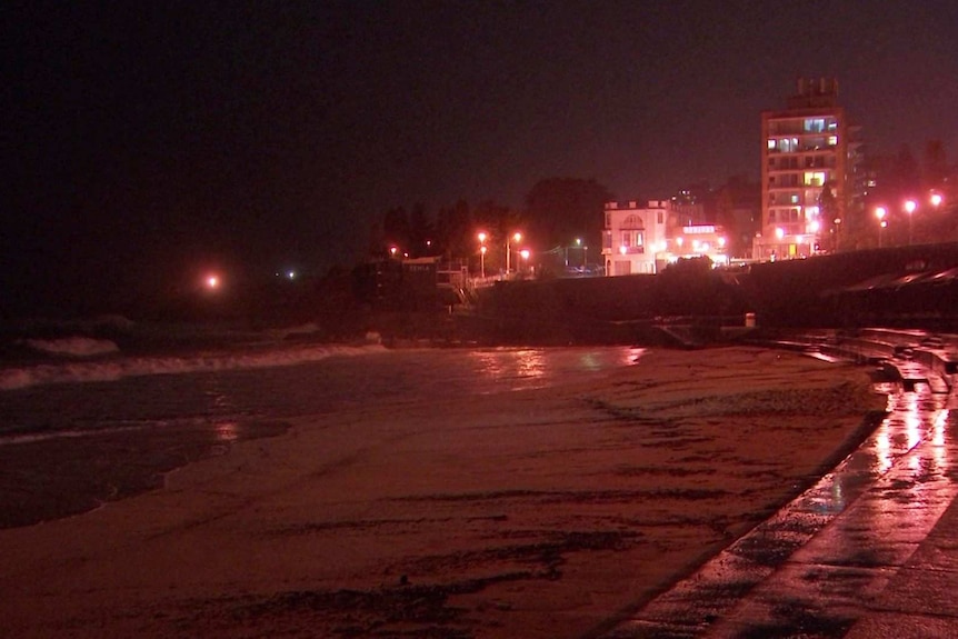 A beach at night with buildings in the background.