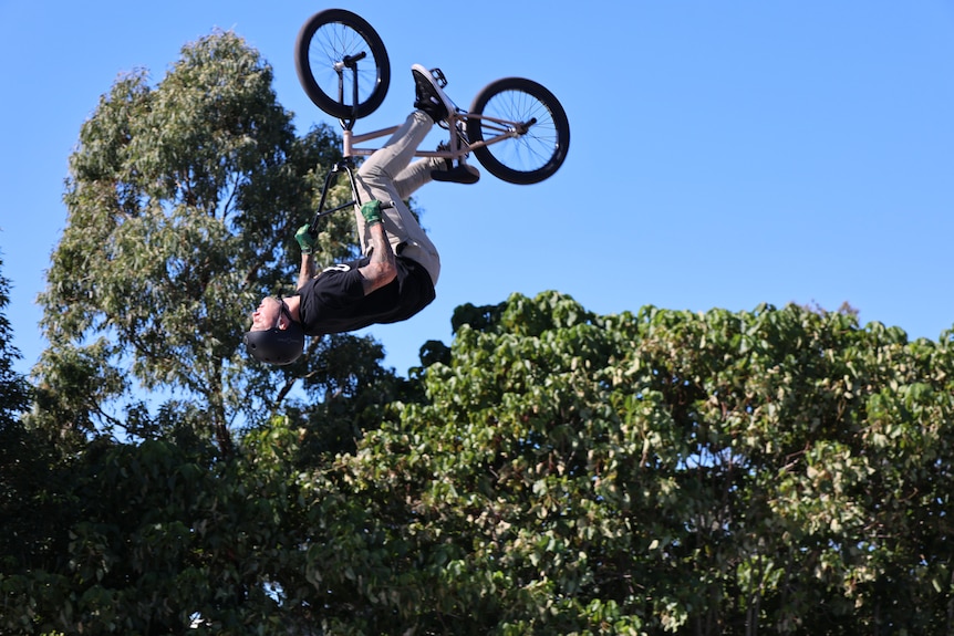 The BMX rider does flips in the air.