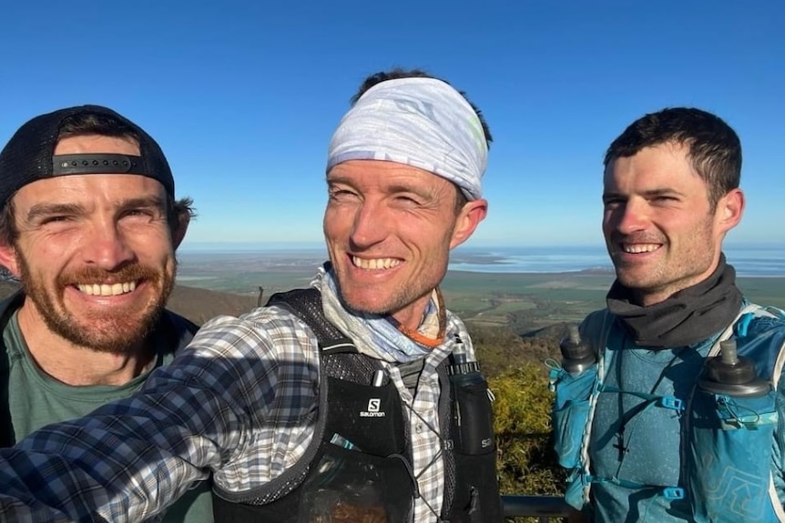 Three young men, grinning in the great outdoors.