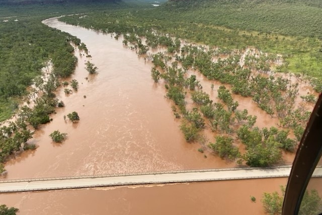 An aerial shot of a bridge with floodwaters around a swollen river