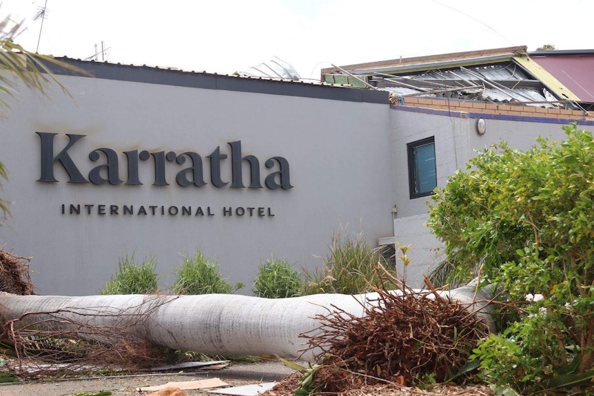 Karratha hotel sign with a tree lying uprooted in front of it.