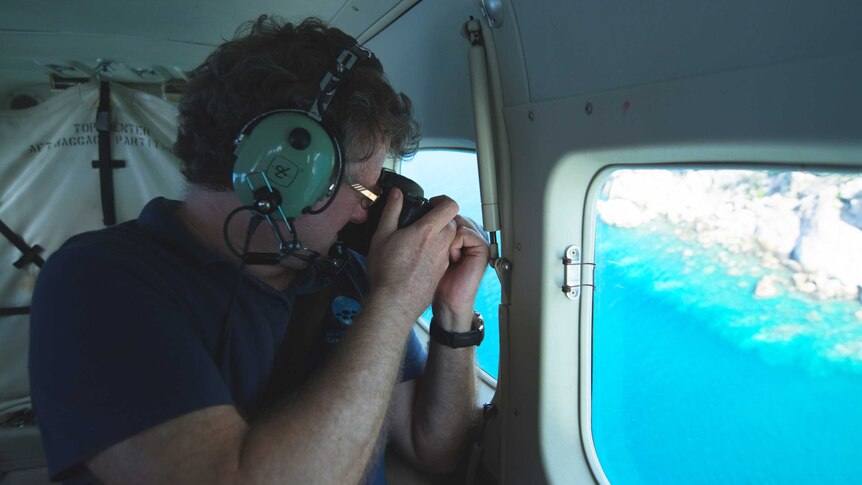 Terry Hughes takes a photo in a plane, with the reef visible through the window.