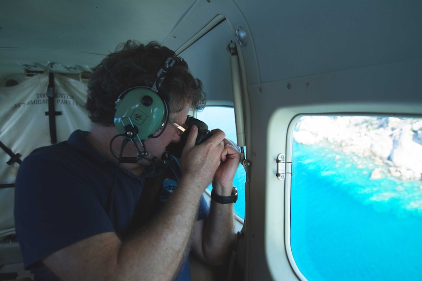 Terry Hughes takes a photo in a plane, with the reef visible through the window.