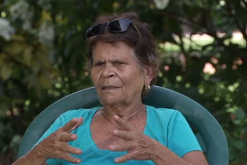 Barbara Cummings sits in a chair outside, gesturing as she speaks.