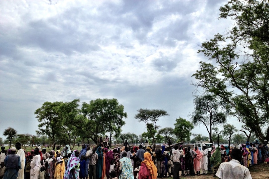 People line up to be transferred to the new camp, Batil.