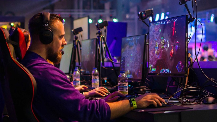 A man plays a game on a computer set up with a webcam for a story about the dark side of game streaming.