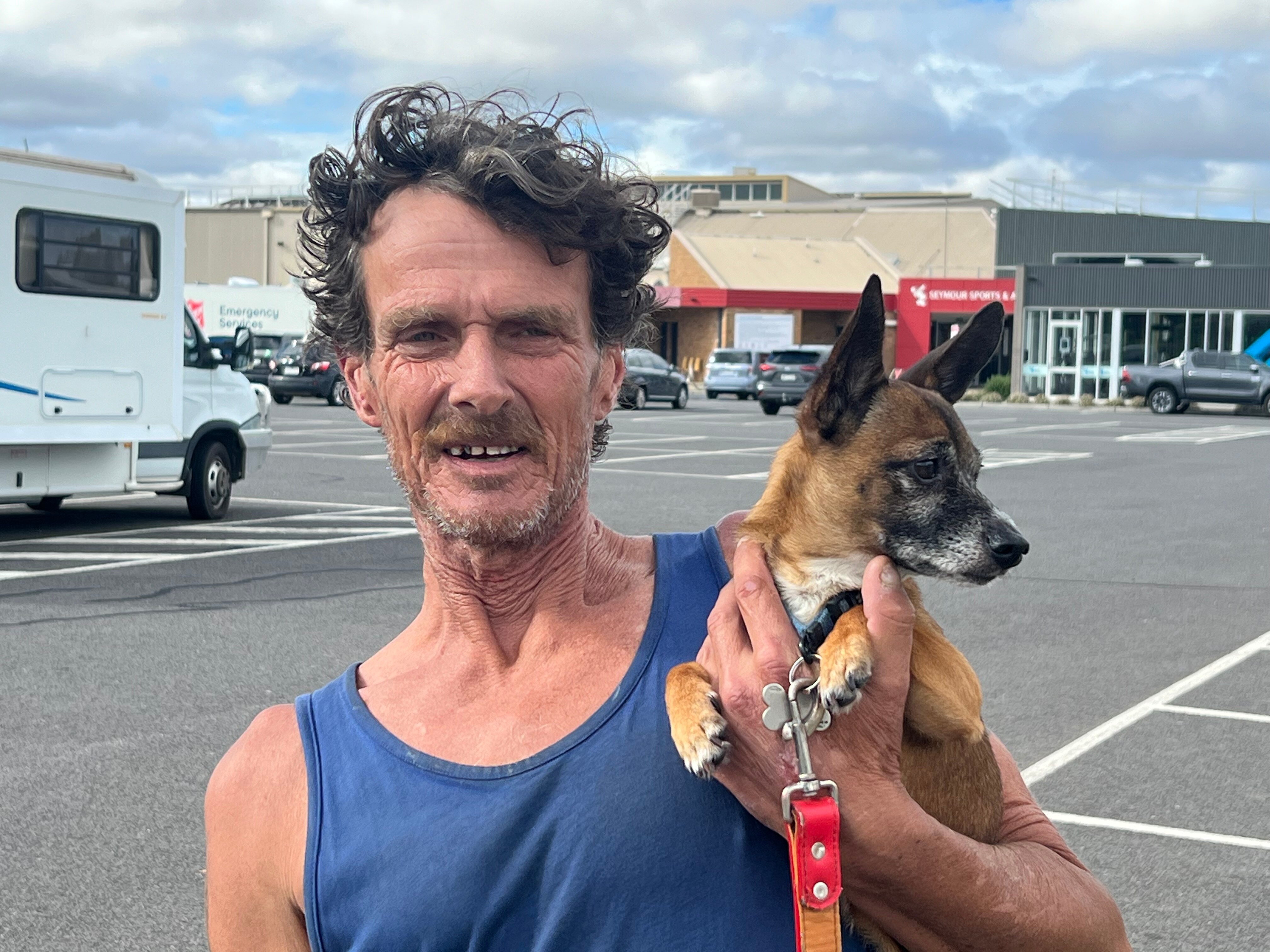 A man wearing a blue singlet and holding a dog
