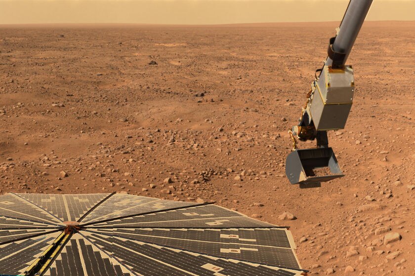 A robotic arm of the Phoenix Mars Lander carries a scoop of Martian soil.